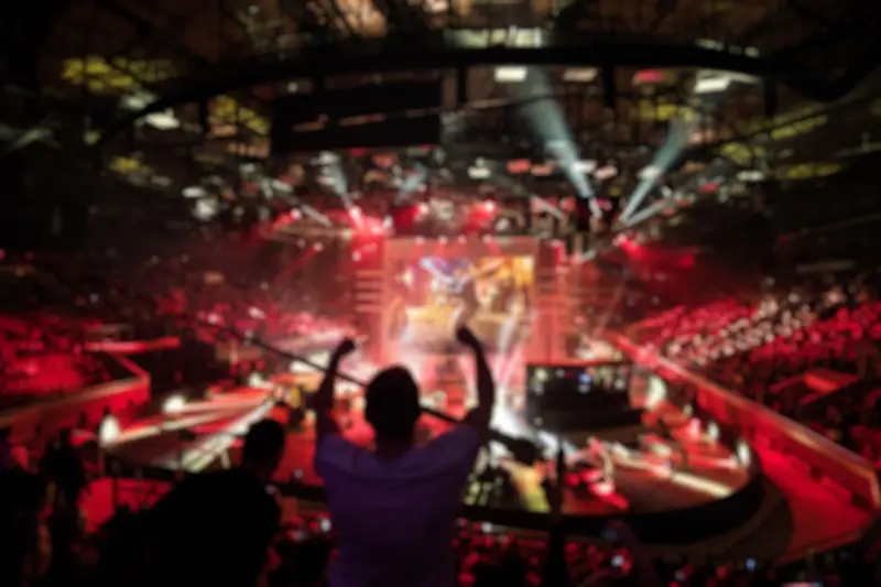 Scène de concert floue avec public en silhouette levant les mains dans une salle éclairée de lumières rouges.