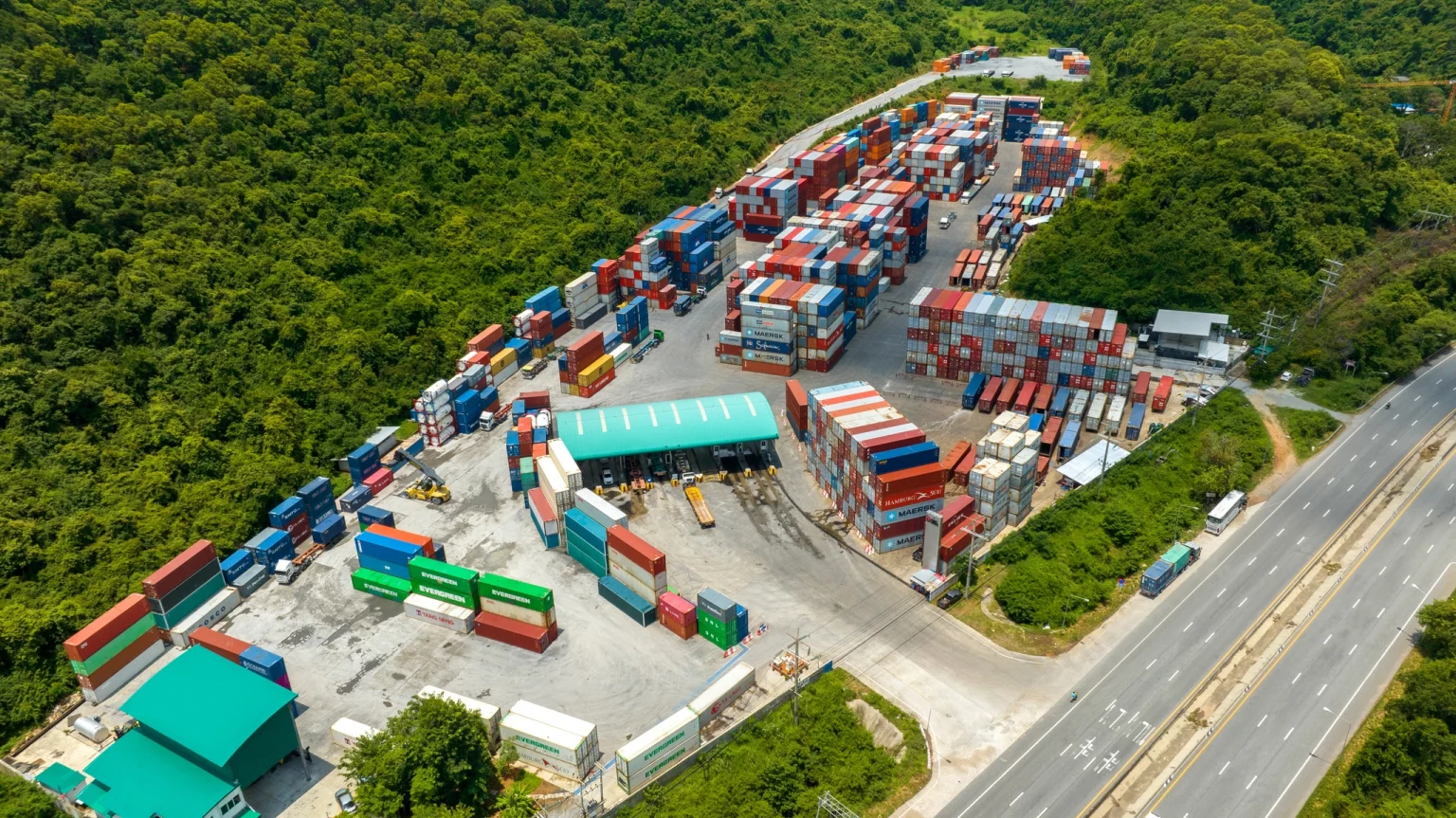 Vue aérienne d'un chantier naval avec des rangées de conteneurs colorés au port maritime, illustrant les services de logistique et de transport maritime.