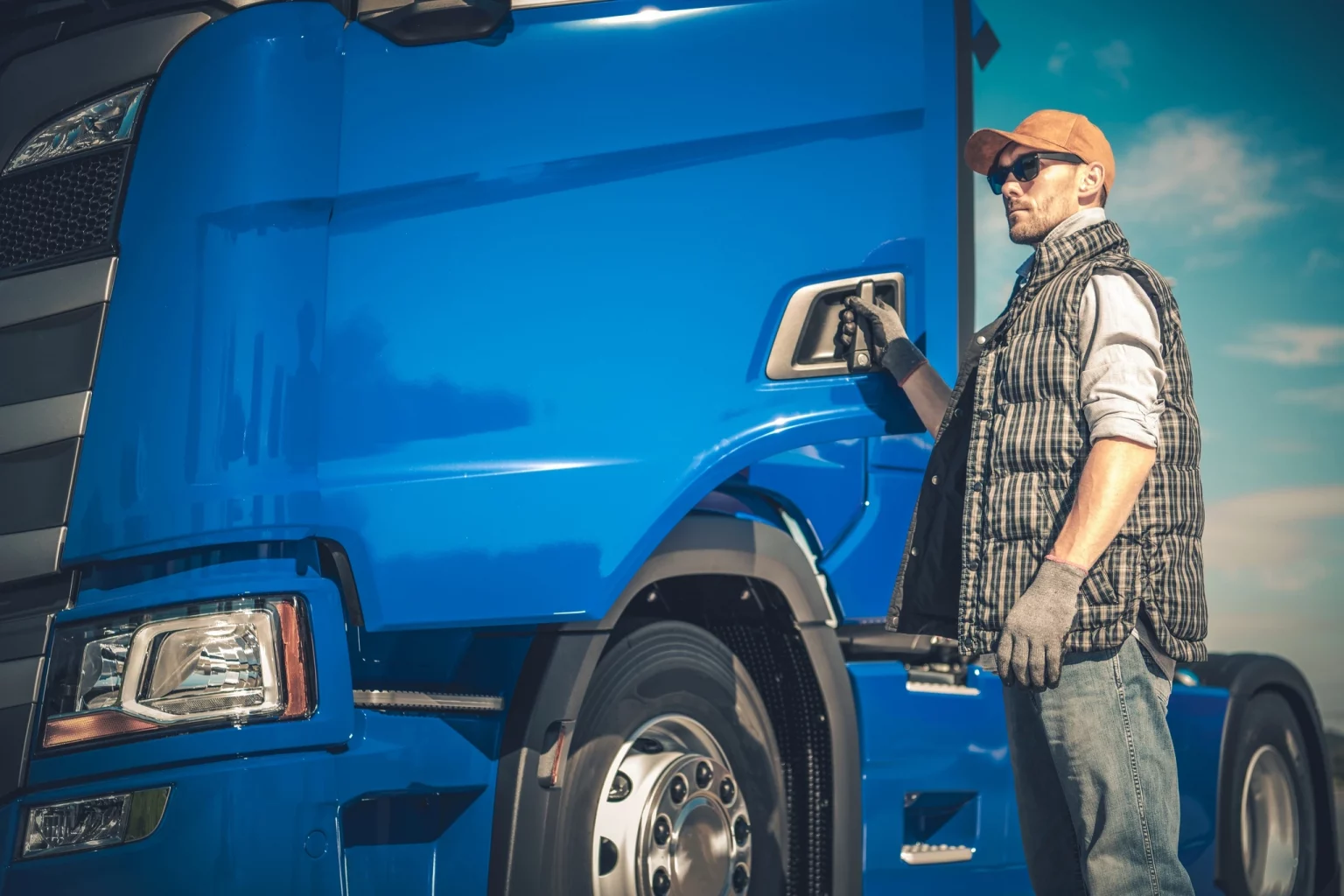 Transporteur professionnel à côté d'un camion bleu, mettant en avant les services dédiés aux conducteurs de poids lourds et à l'industrie du transport routier.