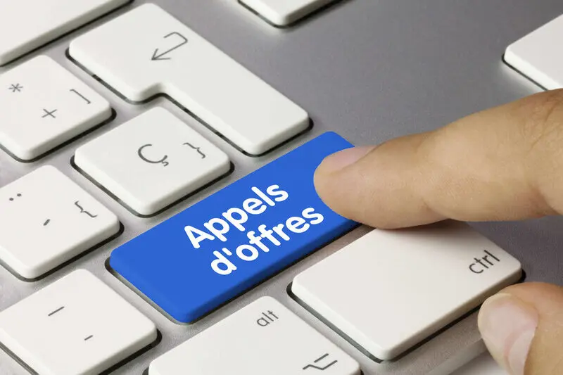 Gros plan sur un bouton 'Appels d'offres' bleu sur un clavier, symbolisant l'engagement d'Innovia dans les appels d'offres publics et privés.