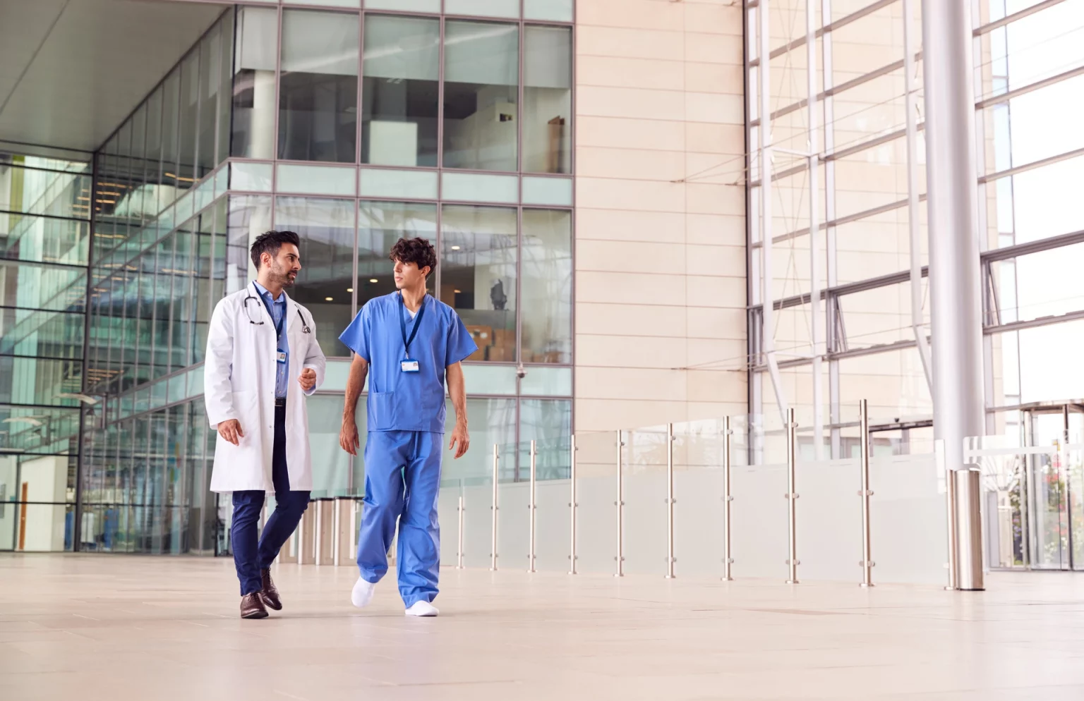 Deux médecins en discussion dans un environnement hospitalier moderne, reflétant l'échange professionnel dans le domaine de la santé.