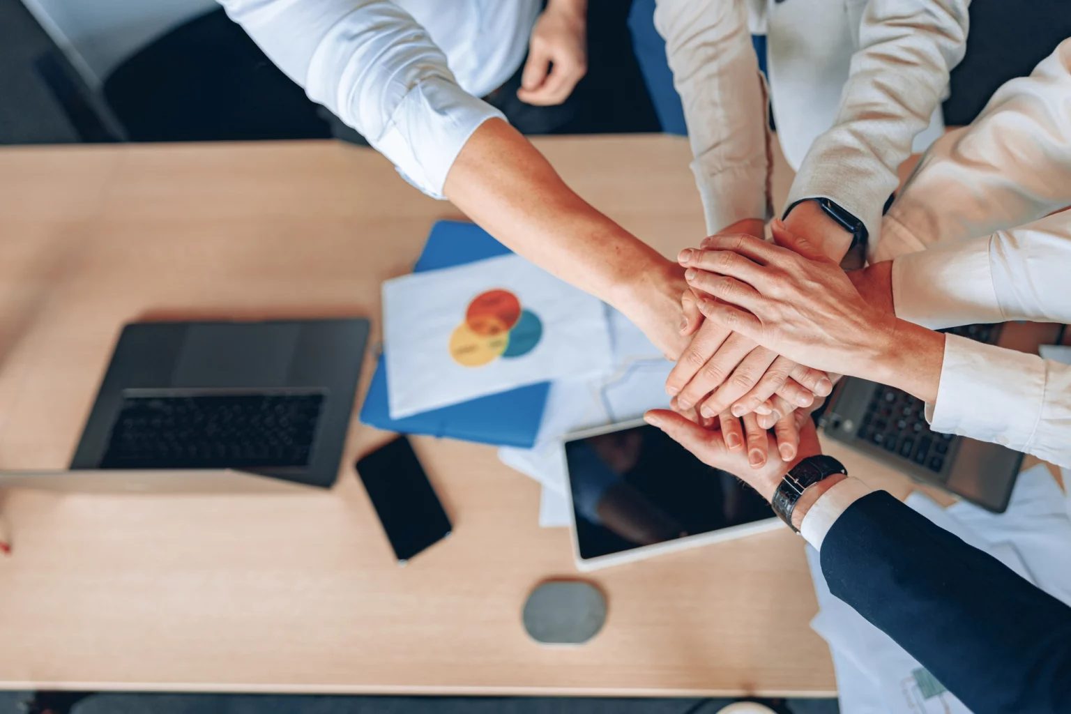 Equipe professionnelle mettant les mains ensemble en signe d'unité et de collaboration pour un impact écologique mesurable chez Innovia.