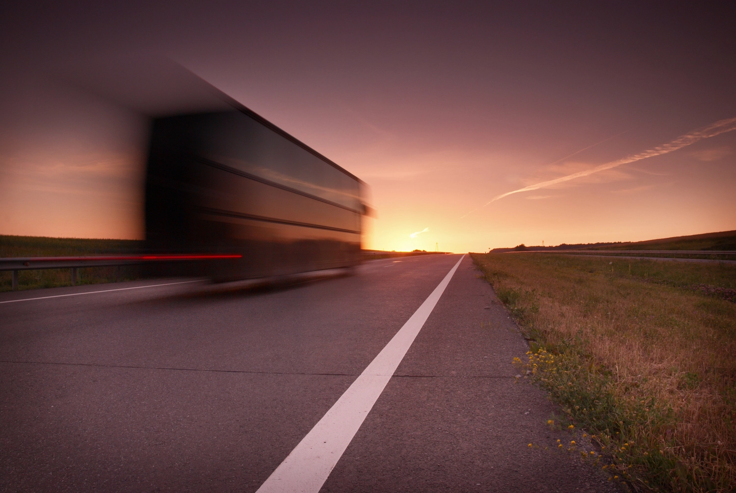 Camion en mouvement rapide sur une autoroute au coucher de soleil, représentant l'efficacité du transport express routier.