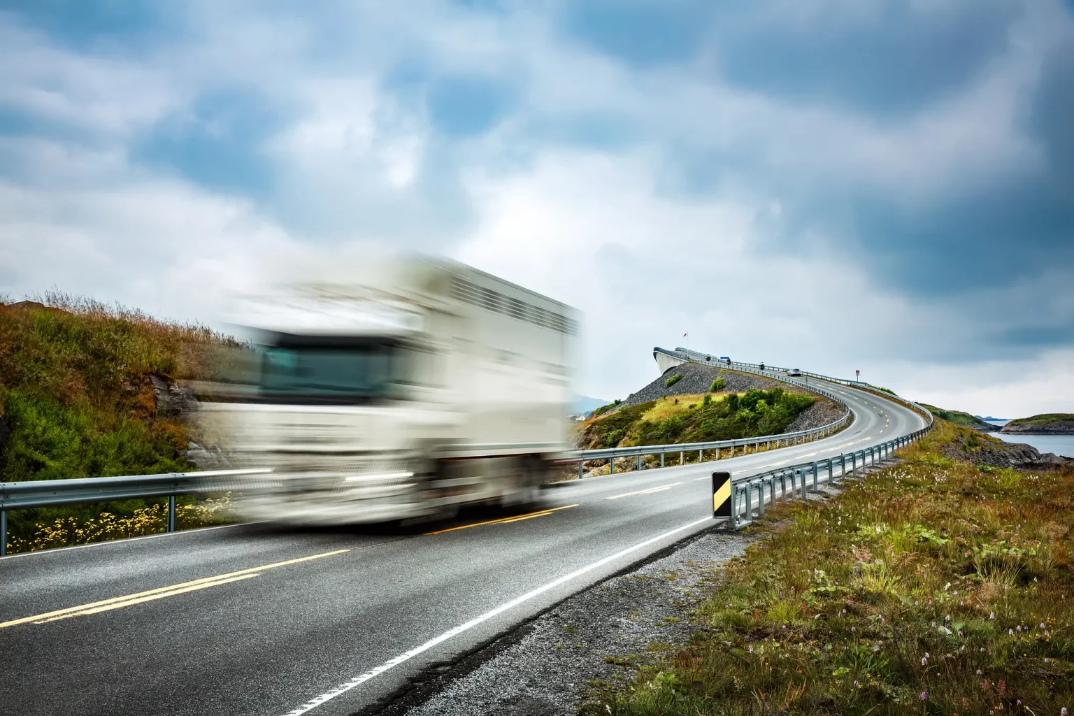 Camion de livraison rapide sur une route sinueuse, symbolisant le service de distribution agile et fiable pour les centrales d'achats.