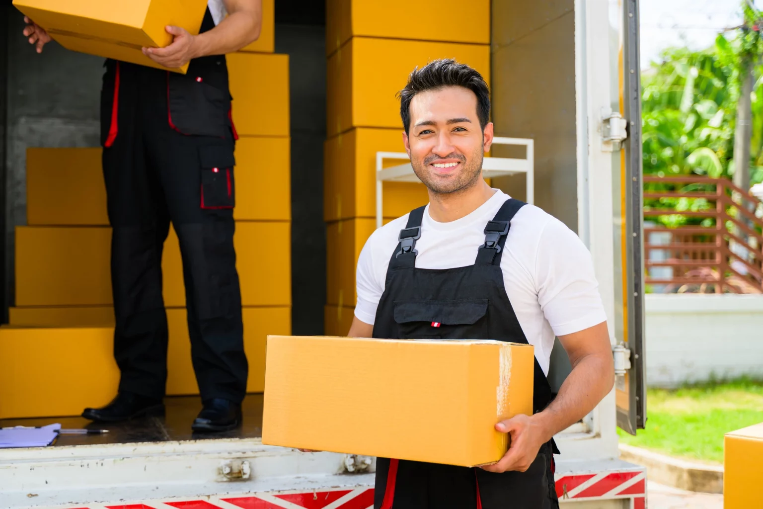 Livreur en uniforme tenant un colis près d'un camion de livraison, reflétant la logistique et la distribution dans le secteur du commerce de détail.