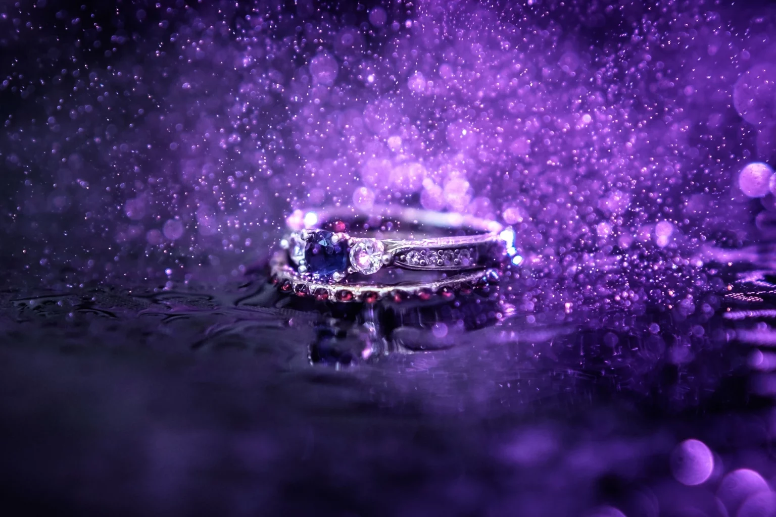 Bague précieuse sertie de pierres sur un fond violet éclatant avec des reflets scintillants et de l'eau.
