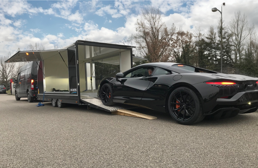 Voiture de sport McLaren noire se déchargeant d'une remorque, mettant en avant le luxe et la performance de haute gamme.
