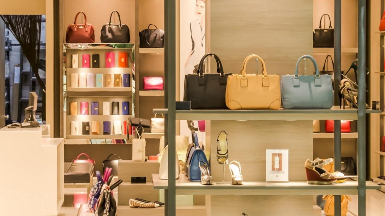 Intérieur d'une boutique de luxe avec étagères éclairées présentant des sacs à main et des accessoires de mode haut de gamme.